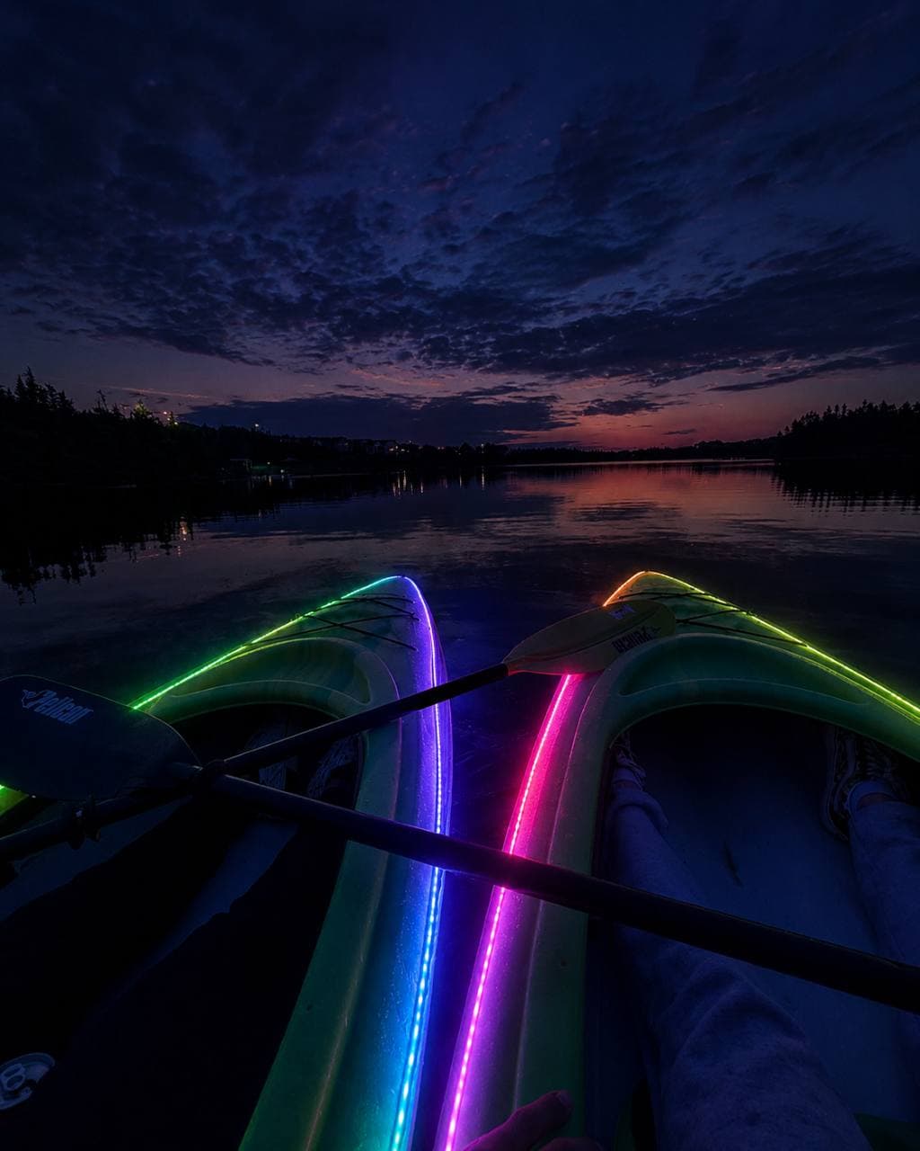 Two RGB LED illuminated kayaks side by side on Neil's Pond at dusk.