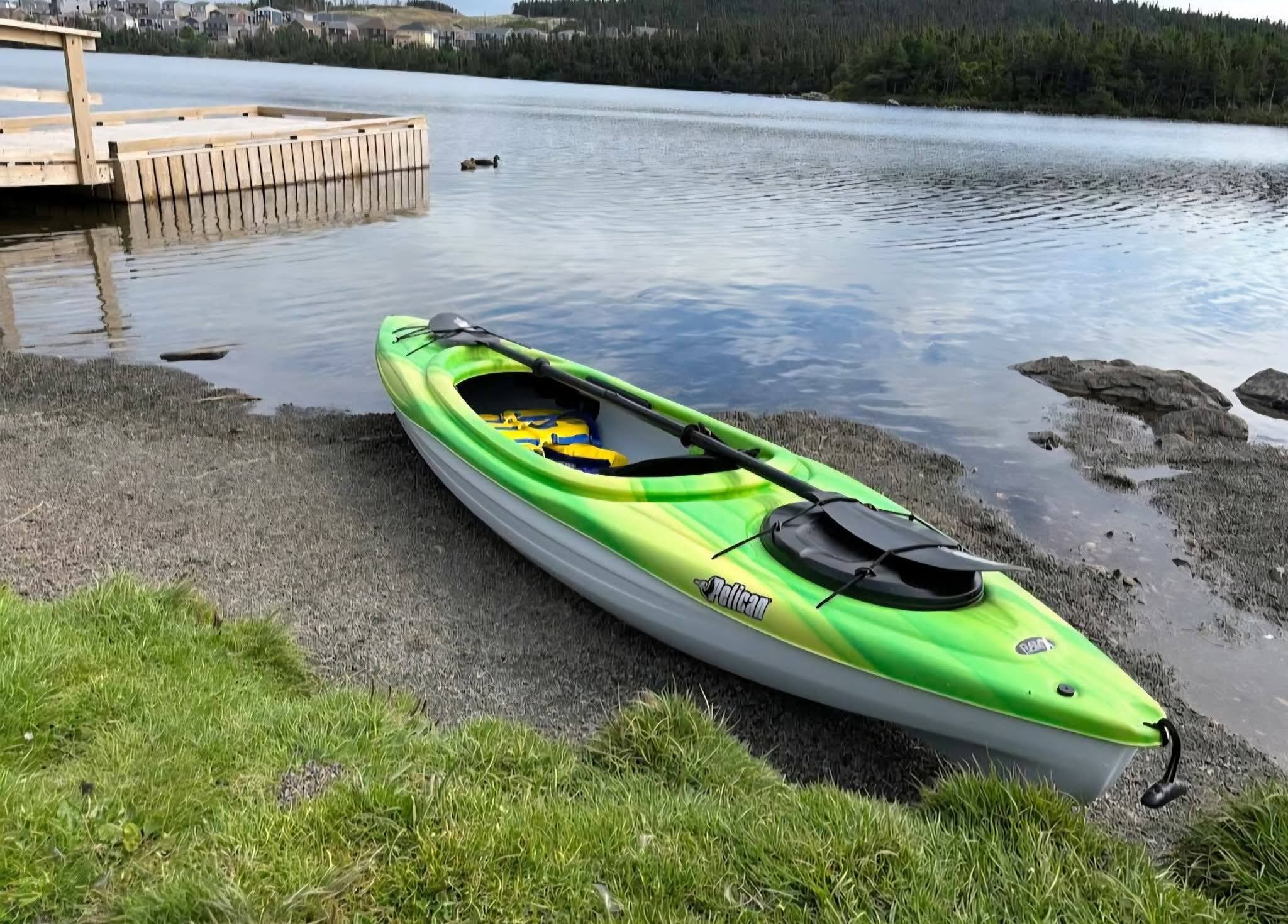 A green Paradise Paddles kayak resting beside Neil's Pond in Paradise, Newfoundland.