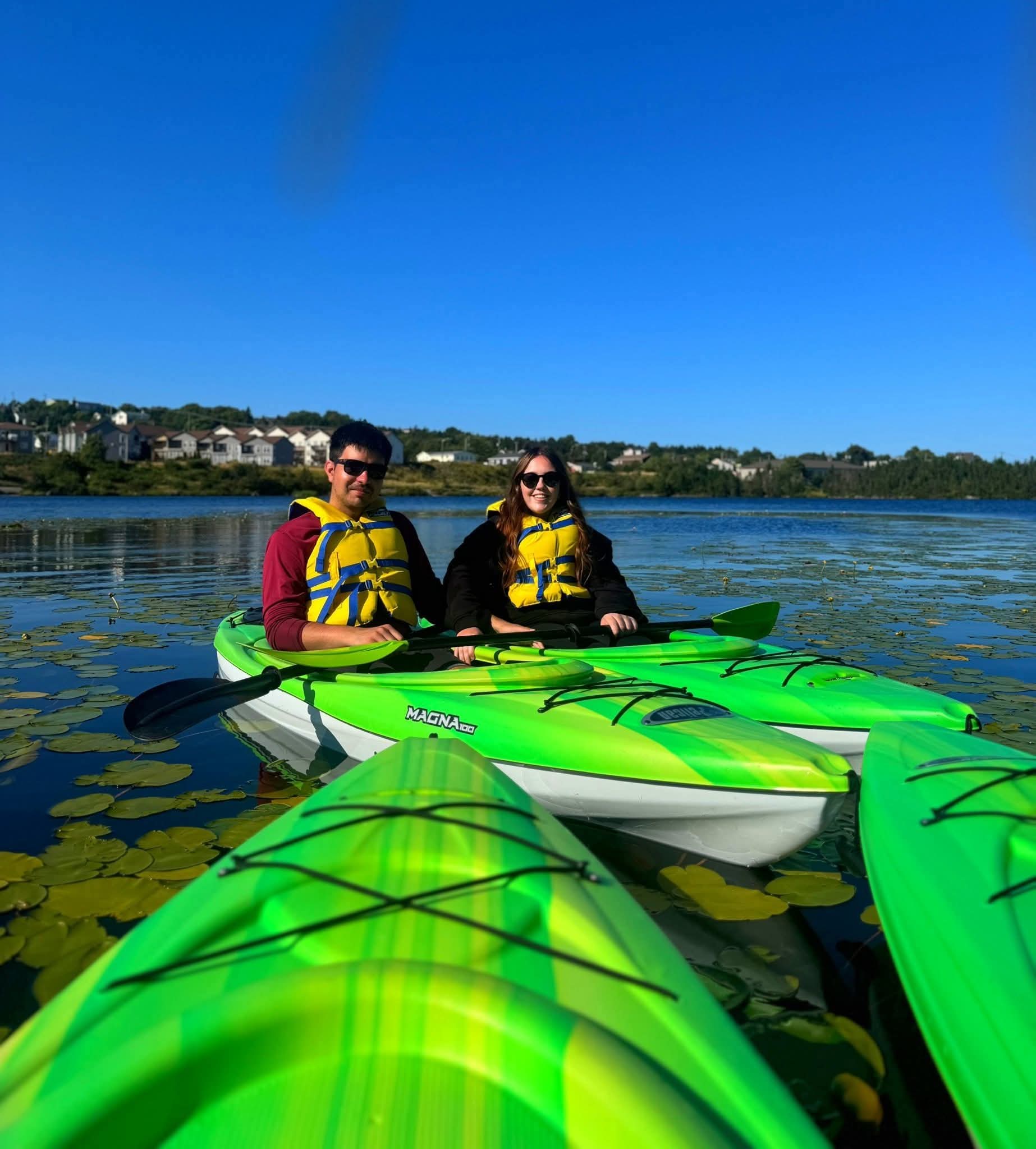 Two paddlers in green kayaks on Neil's Pond in Paradise, Newfoundland.