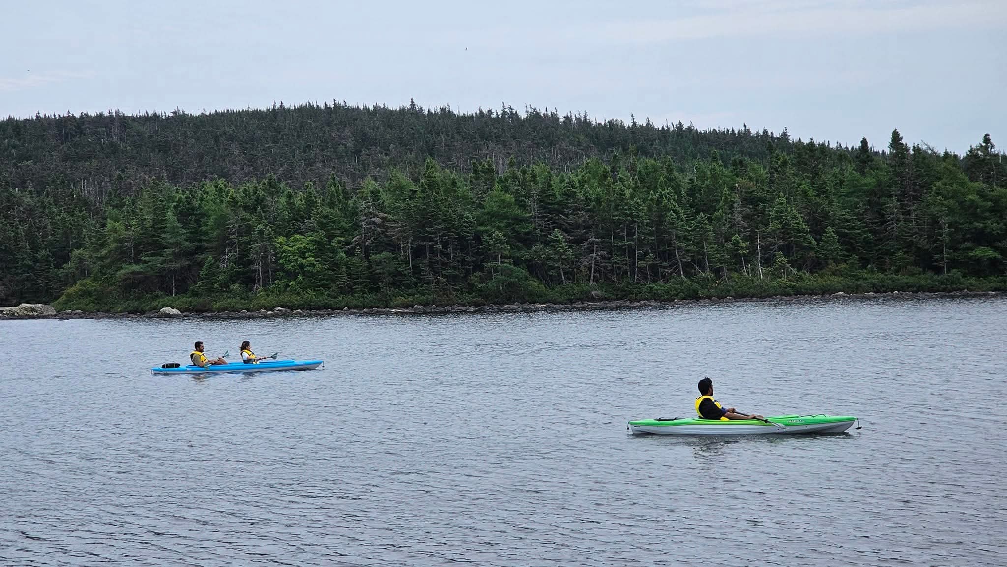 Kayakers paddling across calm Neil's Pond in Paradise, Newfoundland.