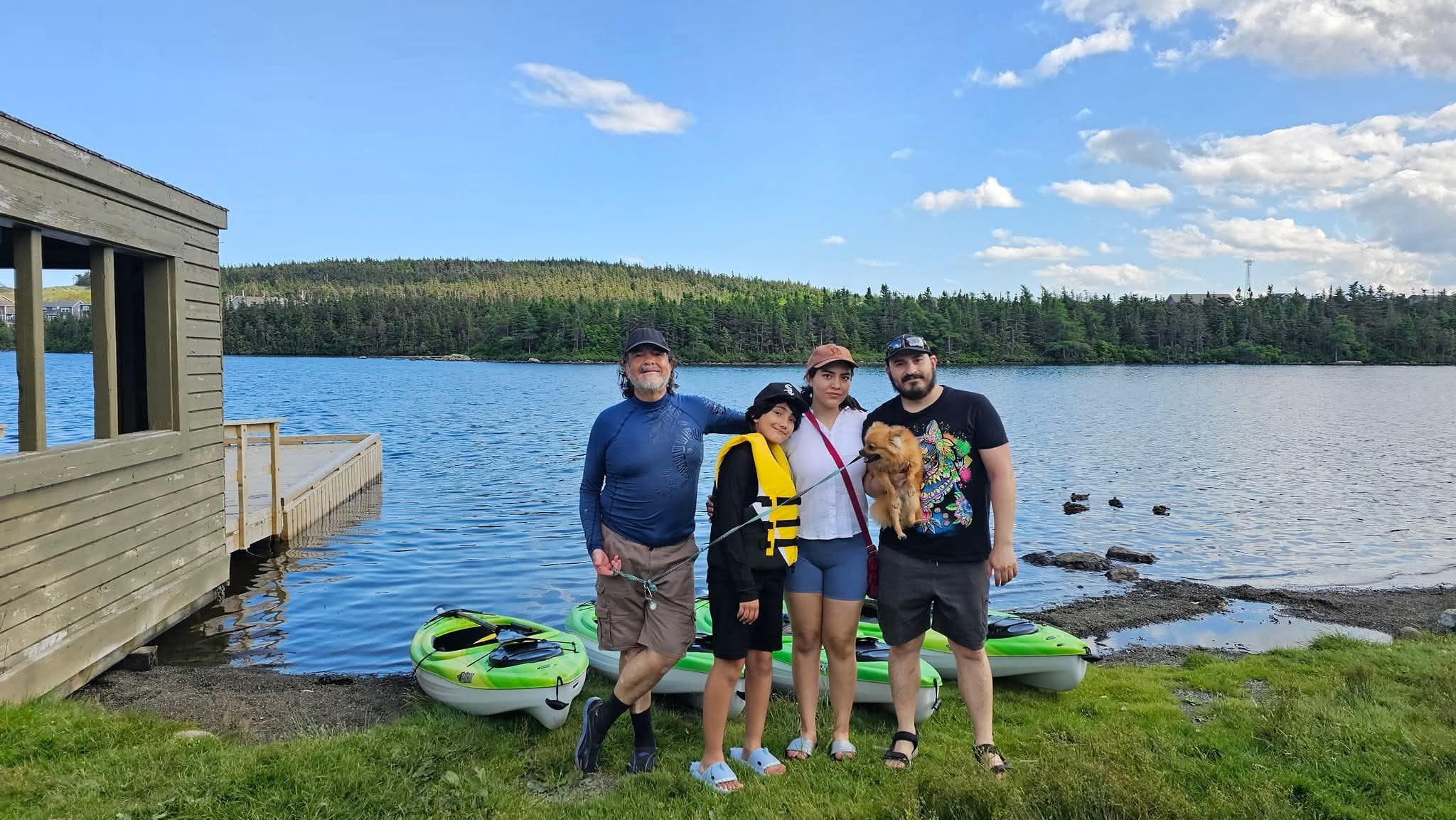 A family standing beside kayaks on Neil's Pond near St. John's, Newfoundland.