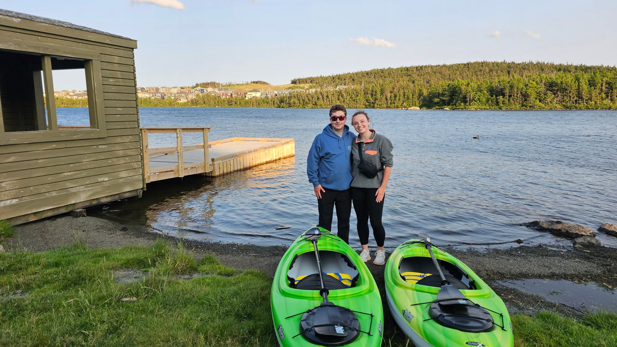 Two paddlers standing beside green kayaks at Neil's Pond near St. John's, Newfoundland.