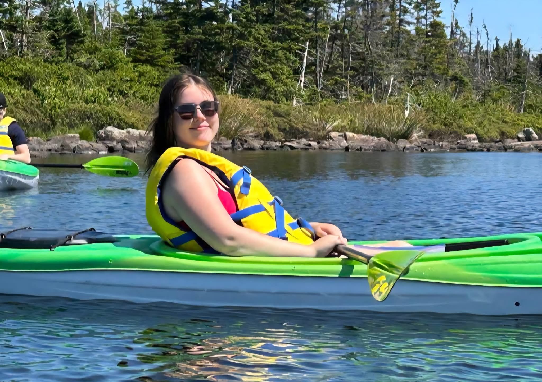 A paddler relaxing in a green kayak on Neil's Pond in Paradise, Newfoundland.